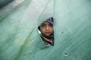 Un bambino guarda attraverso uno squarcio in una tenda montata per ospitare le persone rimaste senza casa dopo il terremoto - Katmandu, Nepal, 27 aprile 2015 (EPA/NARENDRA SHRESTHA)